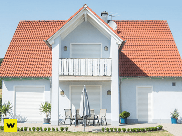 Modernes Einfamilienhaus mit rotem Satteldach, Balkon und möblierter Terrasse.